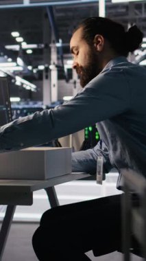 Yapay zeka tarafından değiştirildikten sonra iş yerinde kişisel eşyalarını toplayan dikey video üzgün veri merkezi çalışanı. Sunucu merkezi çalışma masasından eşyaları kaldıran programcı, yapay olarak kovuldu