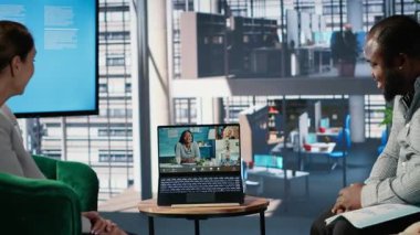 Çok ırklı iş adamları ofis lobisinde bir web video konferansına katılarak, küresel çok kültürlü bir çalışma ortamında uzak ortaklarla strateji ve müzakere noktaları alışverişinde bulundular. Kamera B.