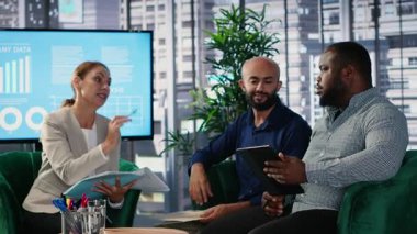 Bir iş toplantısındaki kurumsal liderlik ekibi küresel bir şirketteki idari kararları belirlemek ve yönlendirmek için veri odaklı analizleri ve stratejik düşünceleri kullanır. Kamera B.