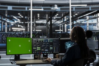 Veri merkezi depolama altyapısında yeşil ekran bilgisayarında çalışan yönetici. Ağ teknolojisiyle dolu sunucu merkezindeki bilgisayar görüntülemesini kullanan bilişim uzmanı