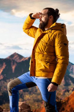 Yürüyüş yolcusu, tepedeki panoramik dağ manzarasına, sonsuz gökyüzüne ve kayalık tepelere hayranlık duymak için ara verir. Zihinsel berraklık için nefes kesici bir zemin oluşturur. Dışarıdaki maceracı..