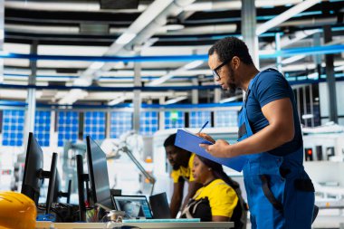 Yenilenebilir enerji tesisinde yazılım sorunları ve performans ölçümleri üzerinde çalışan bir denetleyici, panoda güneş enerjisini test ediyor. İşlemlerde çevre dostu kalite denetimi.