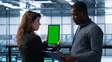 Veri merkezindeki bilgisayar bilimcileri taklit tablet kullanıyor, sunucu donanımlarını denetliyor, cihazları güncelliyor. Krom anahtar cihazı, kamera A kullanılarak dengeli işlemleri sağlamak için işbirliği yapan bilişim bilimci meslektaşları