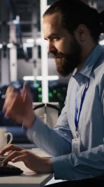 Dikey video sunucu odası bilişim uzmanı ofisteki karmaşık görevler yüzünden hayal kırıklığına uğradı. Stresli mühendis, Veri Merkezi, Kamera A 'da çalışırken sinirsel ağ yazılımı geliştiriyor.