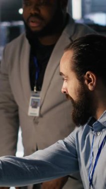 Dikey video sunucusu çiftlik yöneticisi nöral ağ algoritmalarını inceleyen mühendisi denetliyor. Veri Merkezi ekip lideri ve işçi yapay zekanın performans gösterge panellerini inceliyor