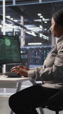 Veri merkezindeki dikey video paniklemiş sistem yöneticisi PC ekranındaki casus yazılım uyarısına tepki veriyor ve acil durum yanıt protokolünü başlatıyor. İşçi hacklenen ekipman sistemlerini tamir etmeye çalışıyor, kamera A