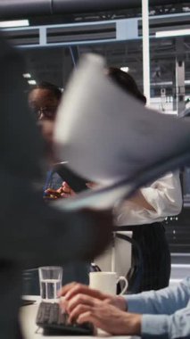 Vertical video yazılım geliştiricileri sunucu çiftliğinde birlikte çalışıyor, nöral ağ kodlarını ve LLM görselleştirme panellerini gözden geçiriyorlar. Takım çalışması veri merkezi meslektaşları AI sistem performansını izliyor