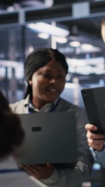 Sunucu odasında birlikte çalışan dikey video veri bilimcileri, sinirsel ağ kodlarını ve LLM görselleştirme panellerini gözden geçiriyorlar. Bilişim uzmanlarından oluşan bir ekip görevleri koordine ediyor, AI sistem performansını izliyor