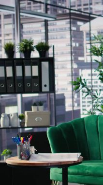 Cam elementler ve üst düzey mobilyalarla dolu, ofis hayatı için düzenlenmiş ve toplantıları ve kurumsal kültürü desteklemek üzere yapılandırılmış parlak ve modern bir yönetim kurulunda kanepenin yer aldığı dikey video iş lobisi