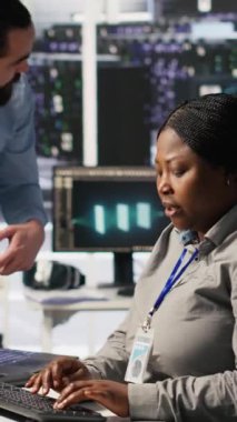 Dikey video sunucu odası yöneticisi AI eğitim verilerini yöneten çalışanlara geri bildirim sağlıyor. Ekip lideri, veri merkezindeki teknisyenle konuşuyor. Sinir sistemini destekleyen sistem operasyonlarını denetliyor.