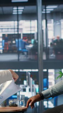 Bir ofiste işbirliği yapan, performans analizi, müzakere ve küresel büyüme ve yatırım sonuçlarına ulaşmak için ortak uzmanlığı kullanan dikey video çeşitliliğindeki iş adamları grubu