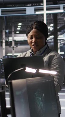 Yazılım güncellemelerini tamamladıktan sonra sinirsel ağ çıktılarından memnun olan dikey video veri merkezi sistem yöneticisiName IT uzmanı gülümsüyor, laptop ekranına bakıyor, yapılandırma sunucu merkezini optimize ediyor