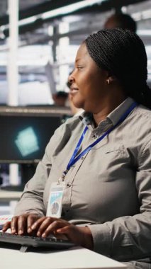 Dikey video veri merkezi bilgisayar bilimcisi PC 'yi kullanarak yapay zeka görselleştirmesini izliyor. Sunucu çiftliği bilişim uzmanı donanımları denetliyor makine öğrenme süreçleri, kamera A