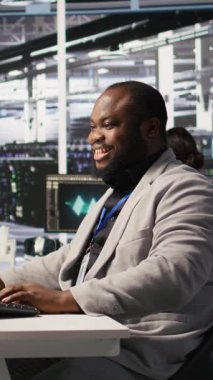 Dikey Veri Merkezi Sistem Yöneticisi sunucuların yapay zeka eğitimi ve çıkarımlarını gözlemliyor. Sunucu odasında çalışan adam bilgisayar sistemlerini denetliyor, derin öğrenmeyi yönetiyor.