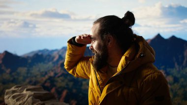 Tatmin olmuş maceracı, dağın zirvesinde kişisel başarısını kutluyor, nefes alıyor ve zirvede manzaranın tadını çıkarıyor. Macera ve açık hava keşfi için motivasyon. Kamera A.