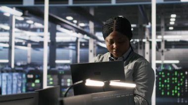 Veri merkezi meslektaşlarının yanındaki mutlu teknisyen portresi yapay zeka tanılarını gözden geçiriyor. Neşeli bilişim uzmanı ve iş arkadaşları operasyonel güvenilirliği korumak için sinirsel ağ performansını analiz ediyor, kamera A