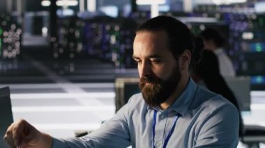 Veri merkezindeki mühendis, iş akışını düzene sokmak ve verimliliği artırmak için çalışma istasyonundaki masa ögelerini yeniden düzenliyor. Görevler sırasında verimliliği optimize etmek için masa başı nesneleri düzenleyen teknisyen, kamera A