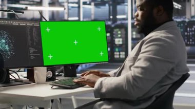 Veri merkezi programcısı yeşil ekranda kodlanıyor, yapay zeka sistemlerini izliyor. Sunucu merkezi bilişim uzmanı, derin öğrenme süreçlerine güç veren sırt çantalarını denetlemek için model bilgisayar kullanır, kamera A