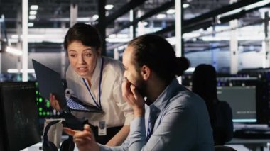 Sunucu odasında beyin fırtınası yapan programcılar, sinirsel ağ kodlarını ve LLM görselleştirme panellerini gözden geçiriyorlar. Veri Merkezi çalışanları yapay zeka sistemlerinin performansını izliyorlar, kamera A