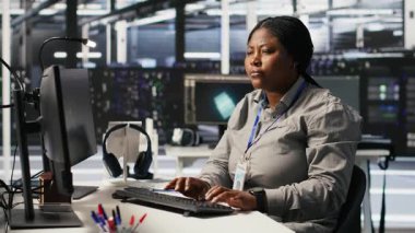 Veri merkezi geliştirici kodlaması PC 'de, yapay zeka süper bilgisayarları için yazılım güncellemeleri yapıyor, saate bakıyor. Sunucu çiftliği bilişim uzmanı yapay zeka ve kamera A kullanarak altyapıyı optimize ediyor.