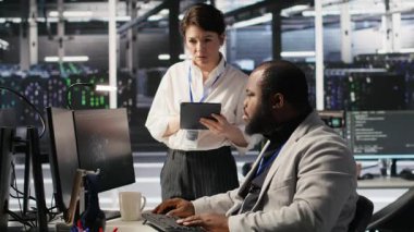 Sunucu odası yöneticisi, derin öğrenme algoritmalarını inceleyen teknisyenleri denetliyor. Veri Merkezi ekip lideri ve Afro-Amerikan çalışan denetimi Yapay Zeka ekipman platformlarının performans göstergesi, kamera A