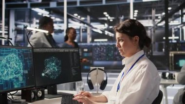 Veri merkezi yazılım geliştiricisi PC kullanarak nöral ağ yapay zeka görüntülemesini izliyor. Sunucu odasında çalışan kadın, donanımlı makine öğrenme işlemlerini denetlemek için bilgisayar kullanıyor, kamera A