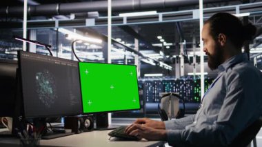 Veri merkezi teknisyeni yeşil ekran model bilgisayar kullanarak yazılım güncellemeleri yapıyor. Sunucu odası bilişim uzmanı, altyapıyı krom anahtar izole ekran PC, kamera A kullanarak optimize ediyor.