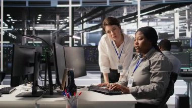 Veri merkezi ekip lideri ve bilişim uzmanı yapay zeka ekipmanlarının performans gösterge panellerini inceliyor. Sunucu odası yöneticisi sistem yöneticisiyle ilgilenir. Ekranda inceleme makinesi öğrenme algoritmaları, kamera A