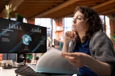 Ofisteki genç şirket analisti bilgisayar ekranında iş sunumunu izliyor, istatistik tablolarını ve performans ölçümlerini inceliyor. Çalışan bilgisayardaki sunum grafiklerine bakıyor.