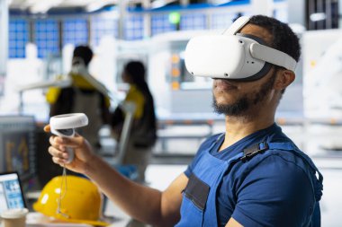 Siyah erkek süpervizör güneş paneli tasarımlarını VR kulaklık üzerinde test ediyor, alternatif enerji üretim tesisinde çalışmak için dijital endüstriyel yazılım kullanıyor. Üretim hattını optimize eden mühendis.