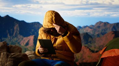 Gezgin vahşi doğada bağlı kalmaya çalışır ama zayıf sinyallerle, dağın tepesindeki tehlikeli rüzgarla mücadele eder. Yürüyüşçü çadırını rüzgarlı bir tepeye kuruyor. Kamera B.