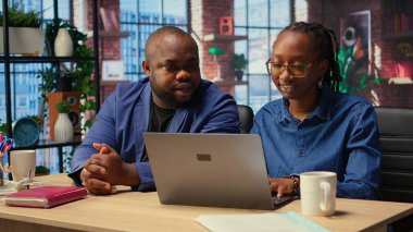 Afrika kökenli Amerikalı yaşam ortakları rahat dairelerinde uzaktan çalışıyor, geliştirme stratejileri planlıyor ve gelişimi izlemek için dizüstü bilgisayar kullanarak proje fikirlerini tartışıyorlar. İşbirliği. Kamera A.