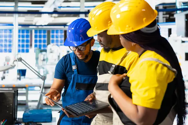 Photovoltaics tesis ekibi güneş panellerini elle inceledi, bilgisayar programındaki performansı izledi. Siyah yöneticiler robotik silah mekanizması parametrelerini okuyor.