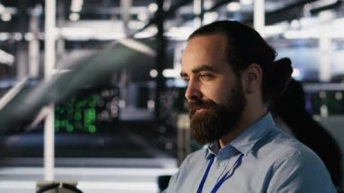 AI LLM görselleştirmesini izlemek için PC kullanan gülümseyen veri merkezi teknisyeni. Sunucu odası çalışanı, yükleme makinelerinin öğrenme süreçlerini denetlemek için bilgisayar kullanıyor. Kamera A