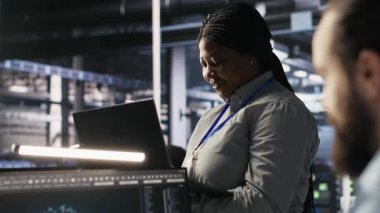 Veri Merkezi yöneticisi denetleme mühendisi bilgisayar çalışma istasyonundaki sinirsel ağları analiz etmek için yazılım geliştiriyor. Ekip lideri ve çalışan gözlemleme sistemi AI sunucu odasında, kamera A