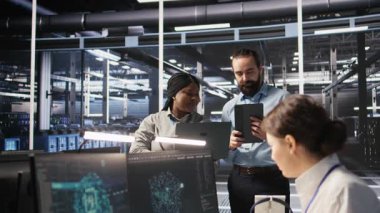 Veri bilimciler sunucu odasında birlikte çalışıyorlar, sinirsel ağ kodlarını ve LLM görselleştirme panellerini gözden geçiriyorlar. Bilişim uzmanlarından oluşan bir ekip görevleri koordine ediyor, AI sistem performansını izliyor, kamera A