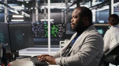 Bilgisayar masasında uzun süre oturduktan sonra yorgun sunucu çiftliği çalışanı geriliyor. Veri merkezindeki yorgun adam kaslarını gevşetiyor, uzun donanım sorun çözme seansından dolayı stresli, kamera A