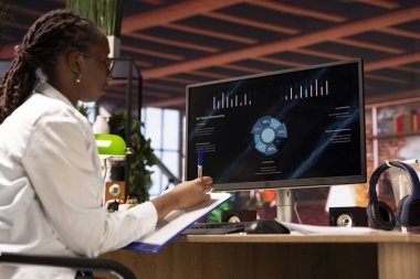 Şirketin gelirini ve giderlerini gösteren bilgisayar ekranında finansal uygulama UI kullanan kadın. Apartmandan çalışan muhasebeci bilgisayar kullanarak yıllık kâr değerlendirmesi yapıyor.