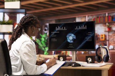 Uzaktan kumandalı işçi iş konferansını PC monitöründen izliyor, bilgi yazıyor. Daire ofisindeki serbest çalışan bilgisayardaki sunum grafiklerine bakıyor, notlar alıyor.