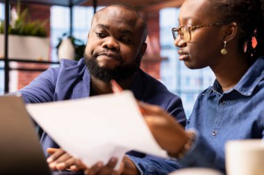 Siyahi çift, çatı katındaki merkez ofiste internet bankacılığı yapıyor, ödemeleri ayarlıyor ve para transferini onaylıyorlar. Memnun erkek ve kadın dizüstü bilgisayardan alışveriş yapıyor..