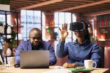 Afrika kökenli Amerikalı bir kadın sanal gerçekliği sanal gerçeklik cihazıyla keşfederken ortağı da uzaktan bilgisayarla çalışıyor. Genç çift evde yapay zekayla modern teknoloji ve aletleri kucaklıyor..