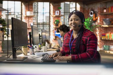 Mutsuz müşterilerle ilgilenen gülümseyen çağrı merkezi ajanının portresi ofis masasında kulaklık kullanarak onlarla konuşuyor. Müşteri destekleme işi yapan mutlu kadın, iş yerinde müşterilerle ilgilenen şikayetler.