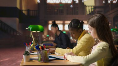 Kütüphanede kitap okuyan genç kızlar zorunlu edebiyat üzerine odaklanmak ve eğitim sırasında akademik müfredat hakkında bilgi kazanmak için. Genç alimler konferans görevlerine odaklanıyor. Kamera A.