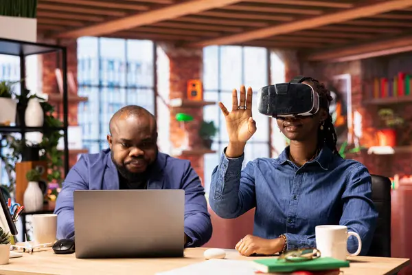 Afrika kökenli Amerikalı bir kadın sanal gerçekliği sanal gerçeklik cihazıyla keşfederken ortağı da uzaktan bilgisayarla çalışıyor. Genç çift evde yapay zekayla modern teknoloji ve aletleri kucaklıyor..