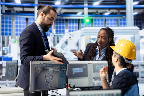Güneş panelleri fabrika yöneticisi çalışanların tablette enerji tüketimini gösteriyor. Photovoltaics tesis yöneticisi işçilerin imalat kaynaklarının kullanımını sunmak için aygıt kullanıyor