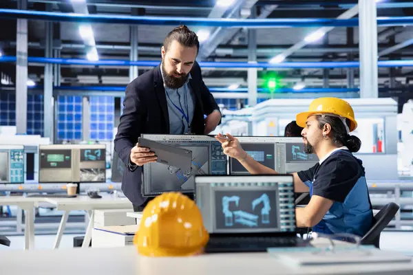 Photovoltaics fabrika müdürü işçilere üretim akışını nasıl optimize edeceğini göstermek için tablet kullanıyor. Sürdürülebilir enerji güneş panelleri fabrika denetleyicisi üretim sürecini izlemek için çalışan aygıtı verir