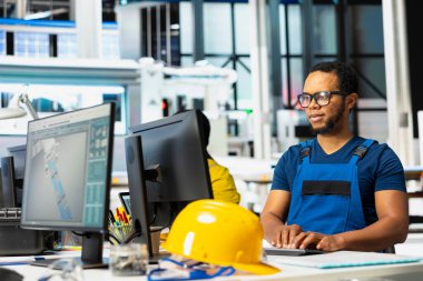 Ofisteki enerji kontrol sistemlerinde, güneş enerjisi imalatıyla çevrili Afrikalı Amerikalı denetleyici. Erkek mühendis fotovoltaik ve endüstriyel üretim hattını dengeliyor.