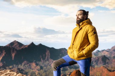 Yürüyüşçü dağların panoramik manzarasına hayran olmak için bir dakikasını ayırır, uzaklığa ve manzaraya bakar. Temiz hava, manzaralı arka plan ve bir kaşif için huzurlu bir ortam..