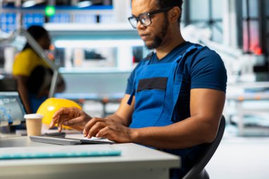 Güneş paneli üretim hattını denetlemek için bilgisayar kullanan erkek teknisyen imalat fabrikasında sürdürülebilir alternatif enerji sağlıyor. Fabrikadaki fotovoltaik sistem sorun çıkarıyor.