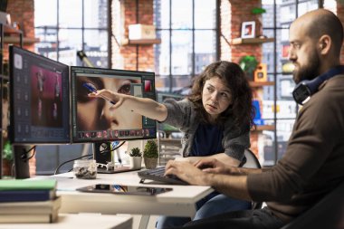 Profesyonel bir stüdyoda bir erkek ve bir kadın fotoğraf rötuşlaması için yapay zeka sistemi kullanıyorlar. Düzenleme yazılımı gelişmiş otomasyon uygular, çarpıcı görüntüler oluşturmada tasarımcılara yardımcı olur.